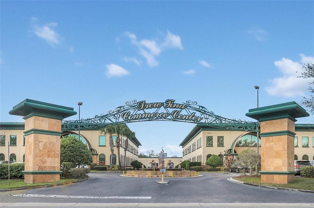 The entrance to the Drew Tina Commerce Center features a decorative metal archway and fountain — 6881 KINGSPOINTE PARKWAY UNIT 11, ORLANDO, FL