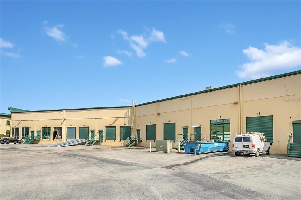 An exterior view of a commercial warehouse building with multiple loading dock doors and bays — 6881 KINGSPOINTE PARKWAY UNIT 11, ORLANDO, FL