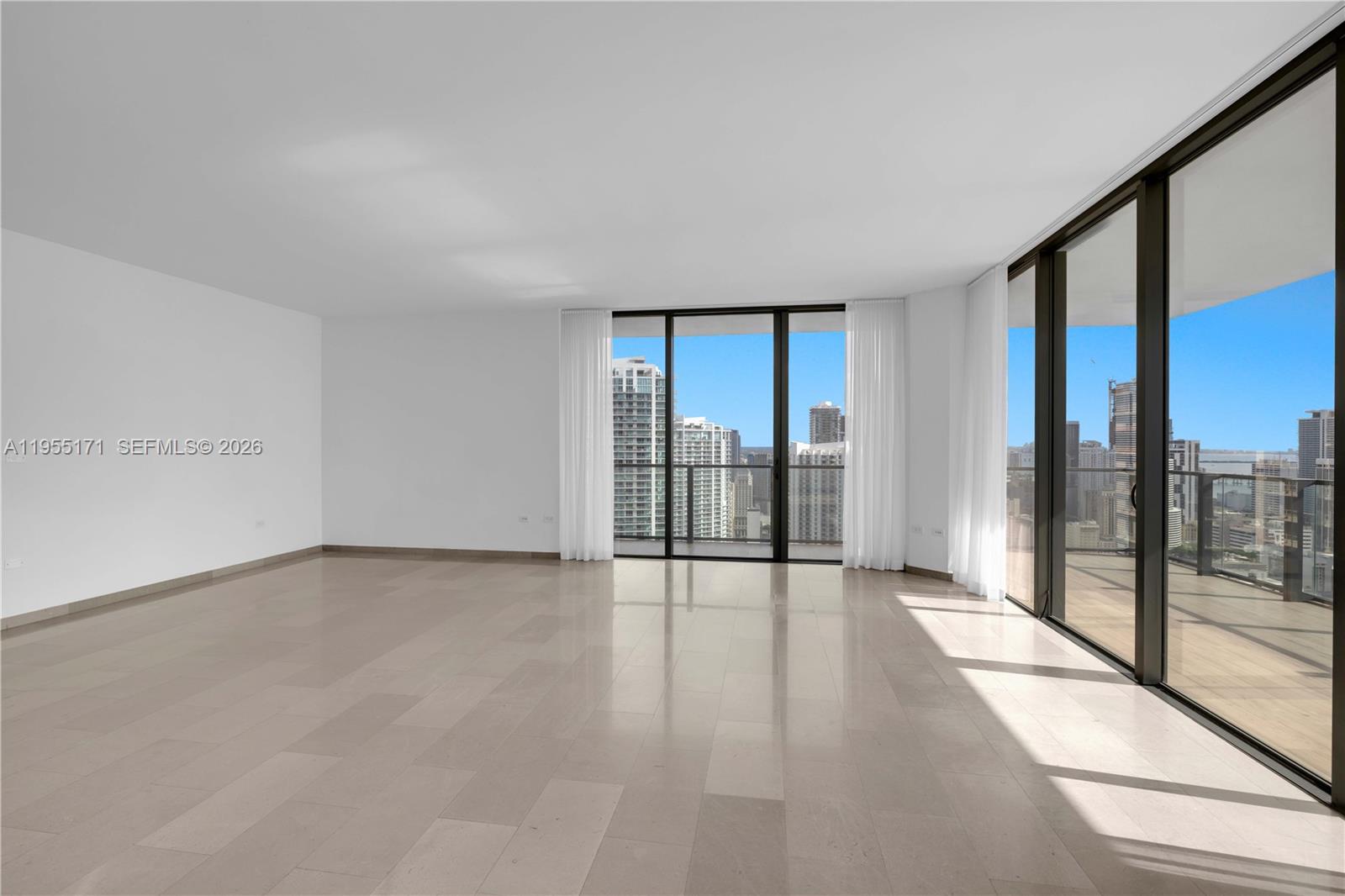 A bright, empty room features light-colored tile flooring, white walls, and floor-to-ceiling windows with city views — 88 SW 7th St # 3711, Miami FL 33130, MIAMI, FL