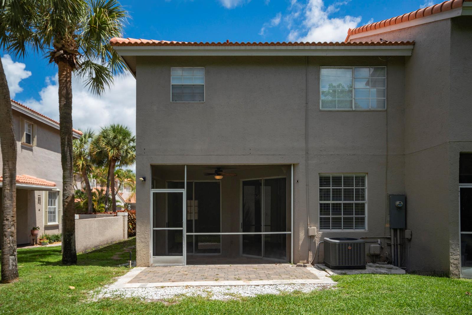 The exterior of a two-story house features a screened-in patio, a paver patio, and an AC unit — 20970 Via Oleander # D, Boca Raton FL 33428, BOCA RATON, FL