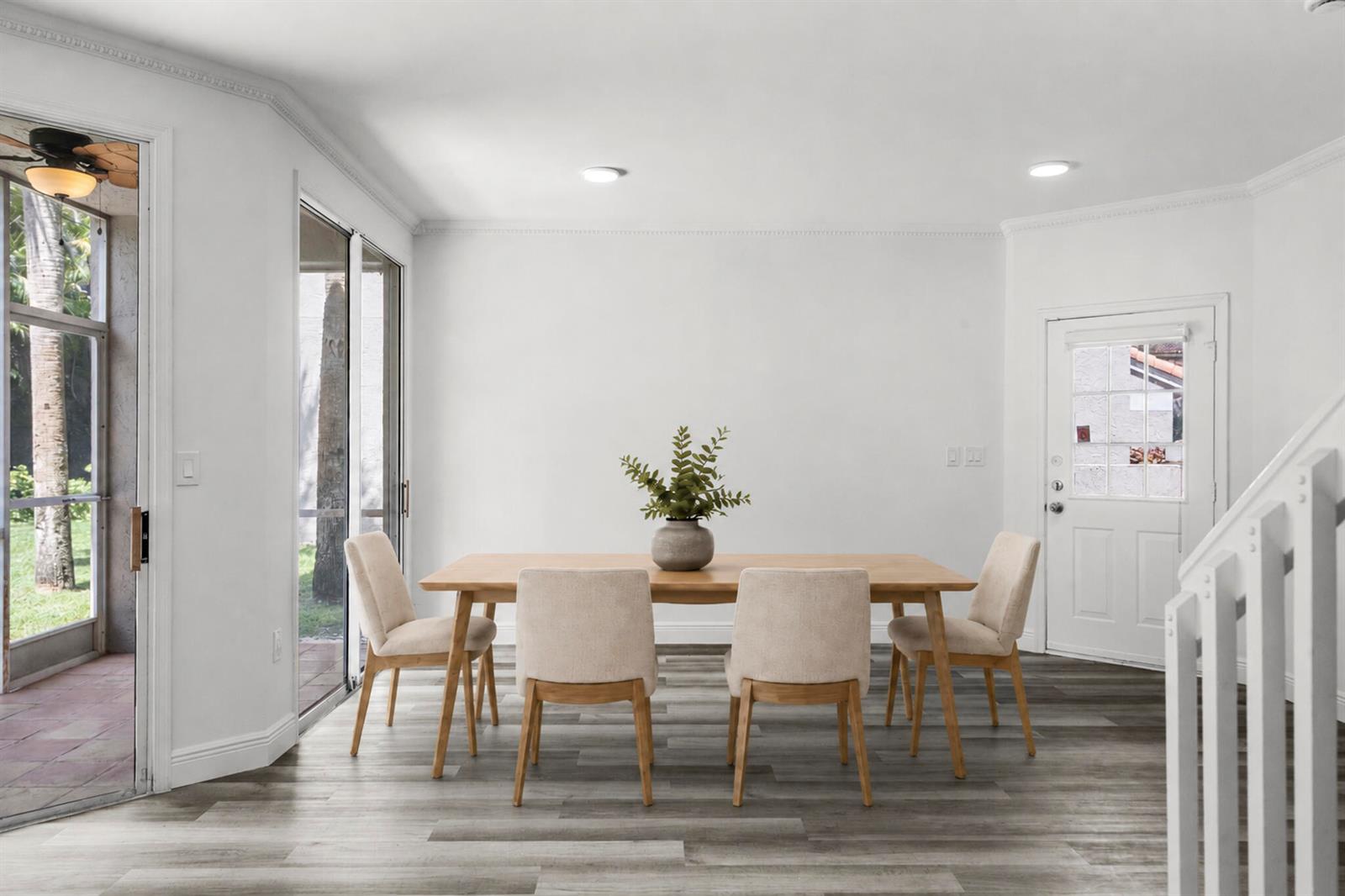 A dining room features a wooden table with four chairs, gray wood-look flooring, and sliding doors — 20970 Via Oleander # D, Boca Raton FL 33428, BOCA RATON, FL