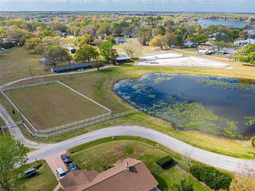 An aerial view shows a house with a driveway, a fenced pasture, and a pond — 3745 LAKE BREEZE DRIVE, LAND O LAKES, FL