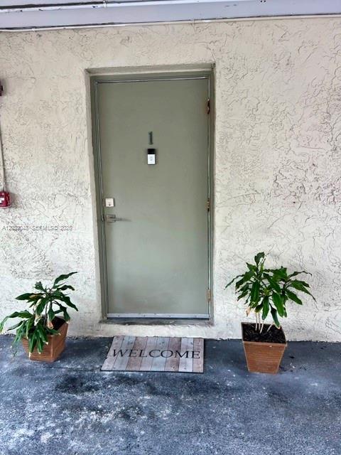 A light green exterior door labeled with the number one sits between two potted plants — 1701 NE 115th st # 1A, Miami FL 33181, MIAMI, FL