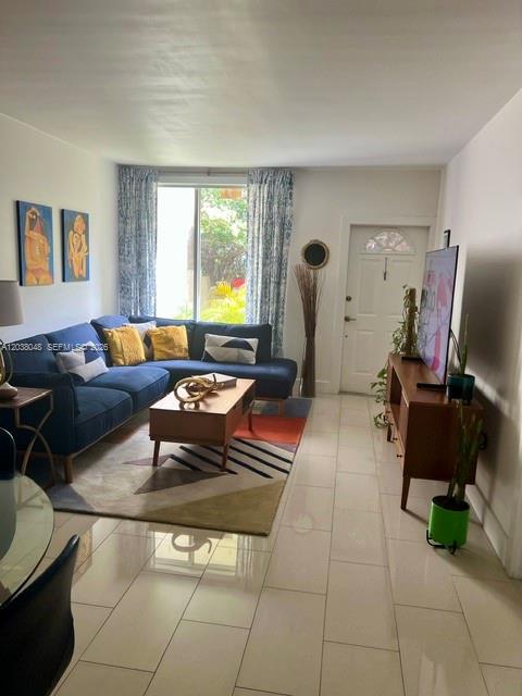 A living room features a blue sectional sofa, a wooden coffee table, and tile flooring — 1701 NE 115th st # 1A, Miami FL 33181, MIAMI, FL