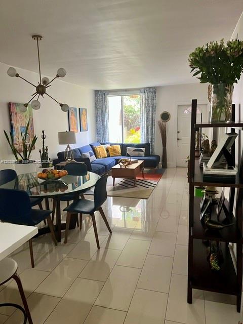 A living and dining area features a blue sectional sofa, glass table, and tile floors — 1701 NE 115th st # 1A, Miami FL 33181, MIAMI, FL