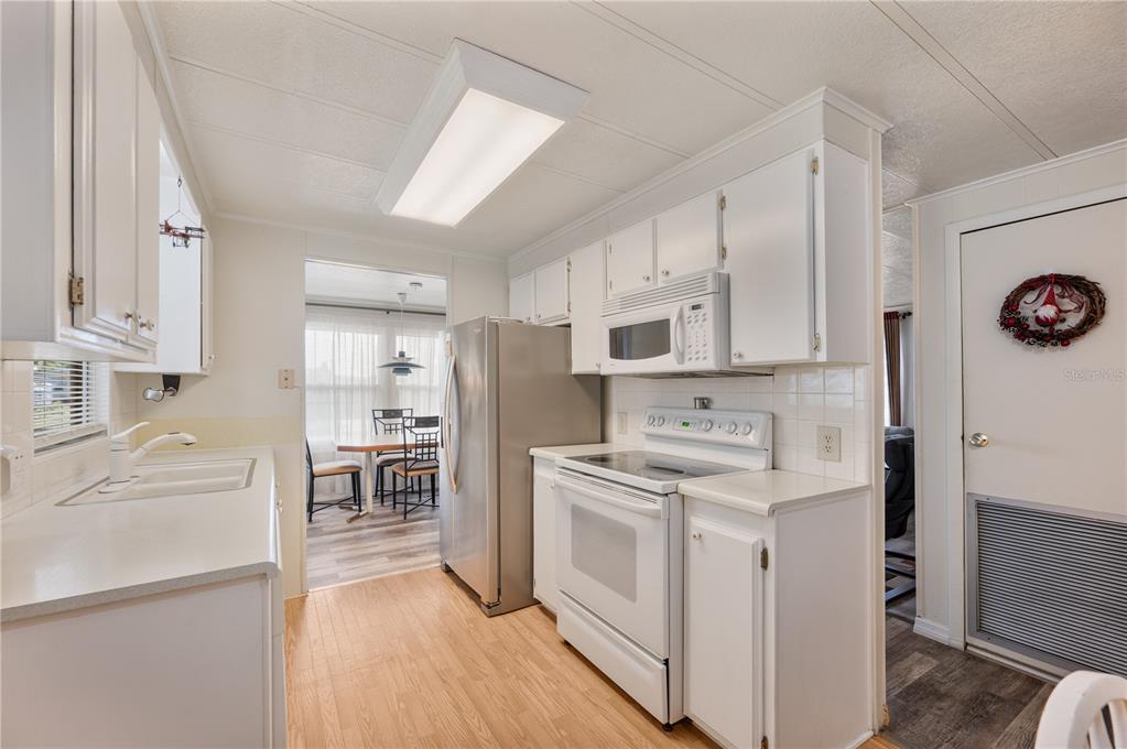 A kitchen features white cabinets, stainless steel appliances, and light wood-look flooring — 1610 REYNOLDS ROAD UNIT 126, LAKELAND, FL