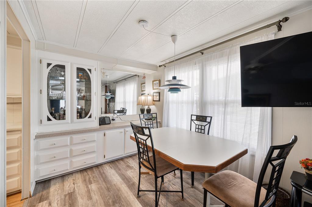A dining room features a white built-in hutch, wood-look flooring, and a modern pendant light — 1610 REYNOLDS ROAD UNIT 126, LAKELAND, FL