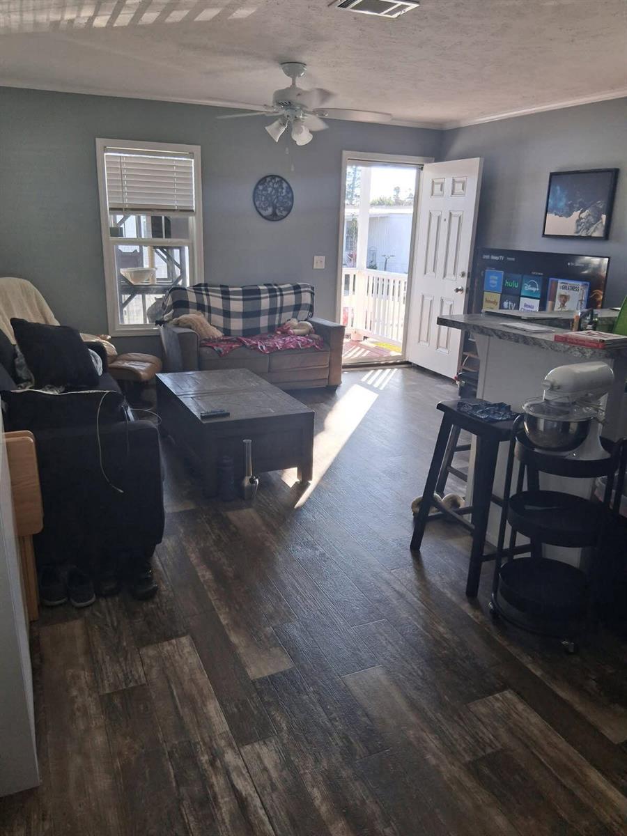A living room with wood-look flooring, a ceiling fan, a sofa, and an open doorway — 356 Mockingbird Avenue, Fort Pierce FL 34982, FORT PIERCE, FL