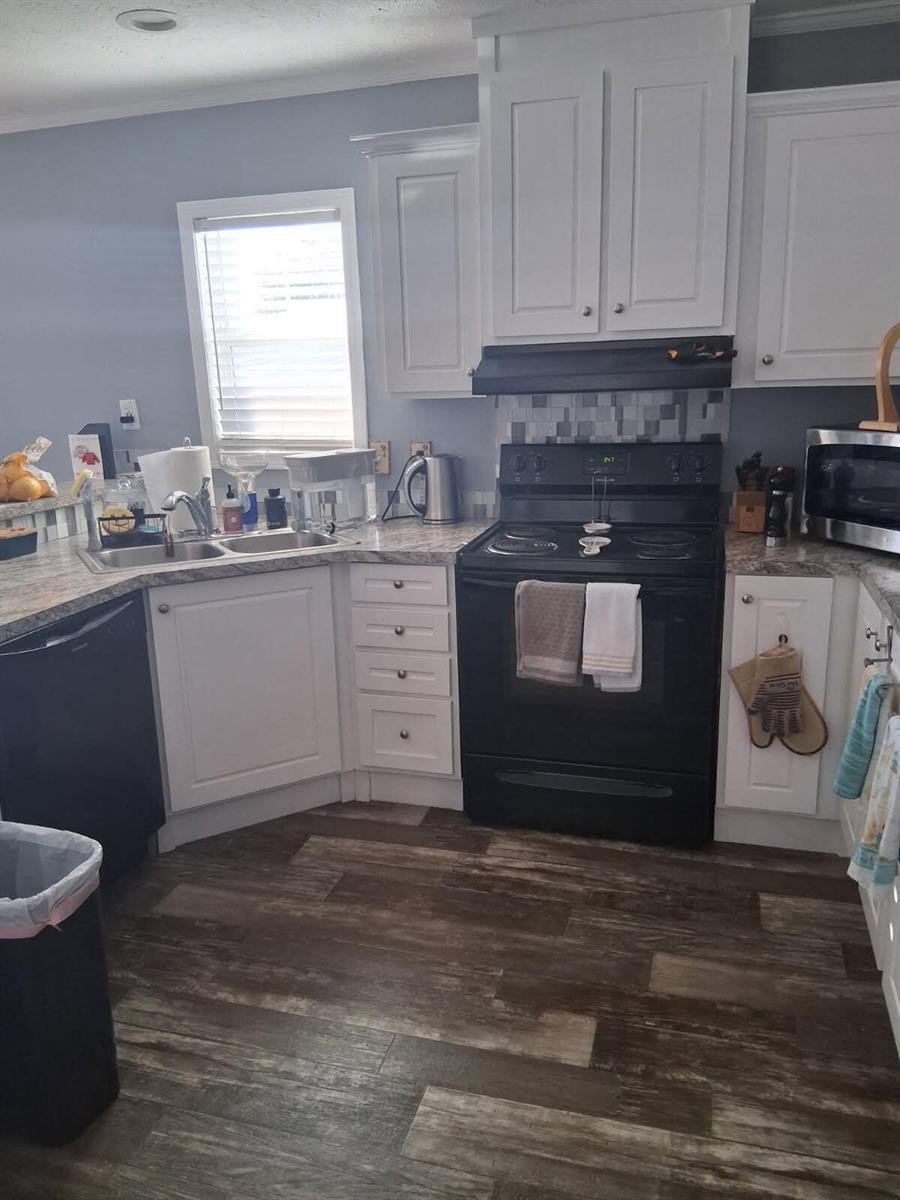 A kitchen features white cabinets, black appliances, a patterned backsplash, and wood-look flooring — 356 Mockingbird Avenue, Fort Pierce FL 34982, FORT PIERCE, FL