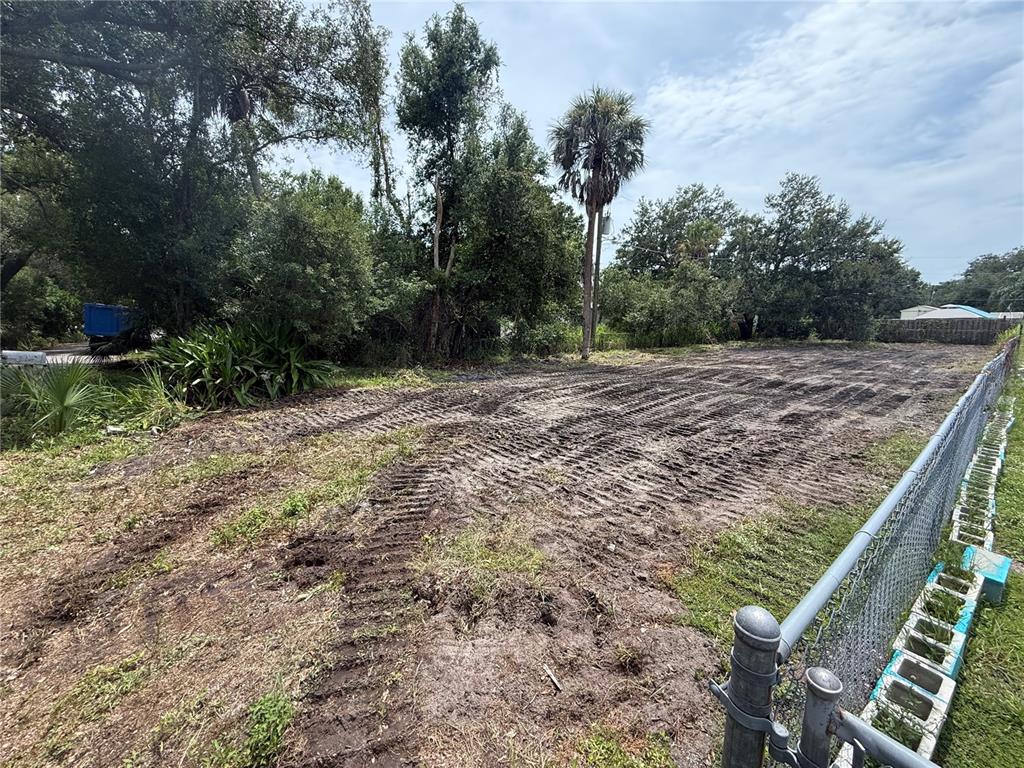 A cleared, dirt-covered vacant lot is bordered by a chain-link fence and mature trees — 103 IRENE STREET N, NOKOMIS, FL