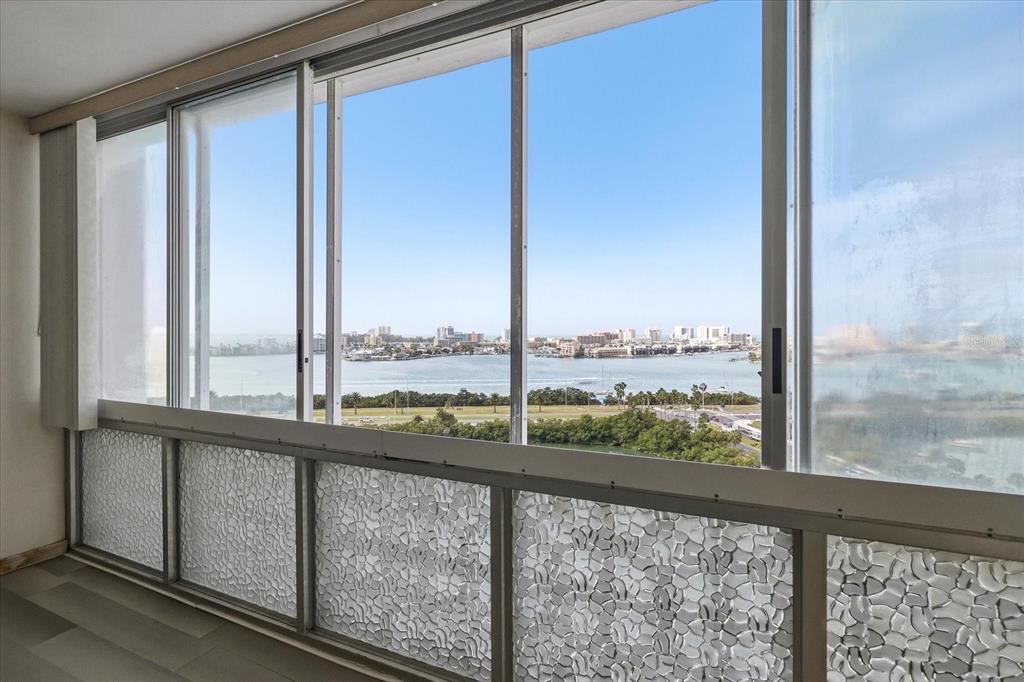 A room with floor-to-ceiling windows featuring textured glass panels and a view of the water — 31 ISLAND WAY UNIT 1205, CLEARWATER BEACH, FL