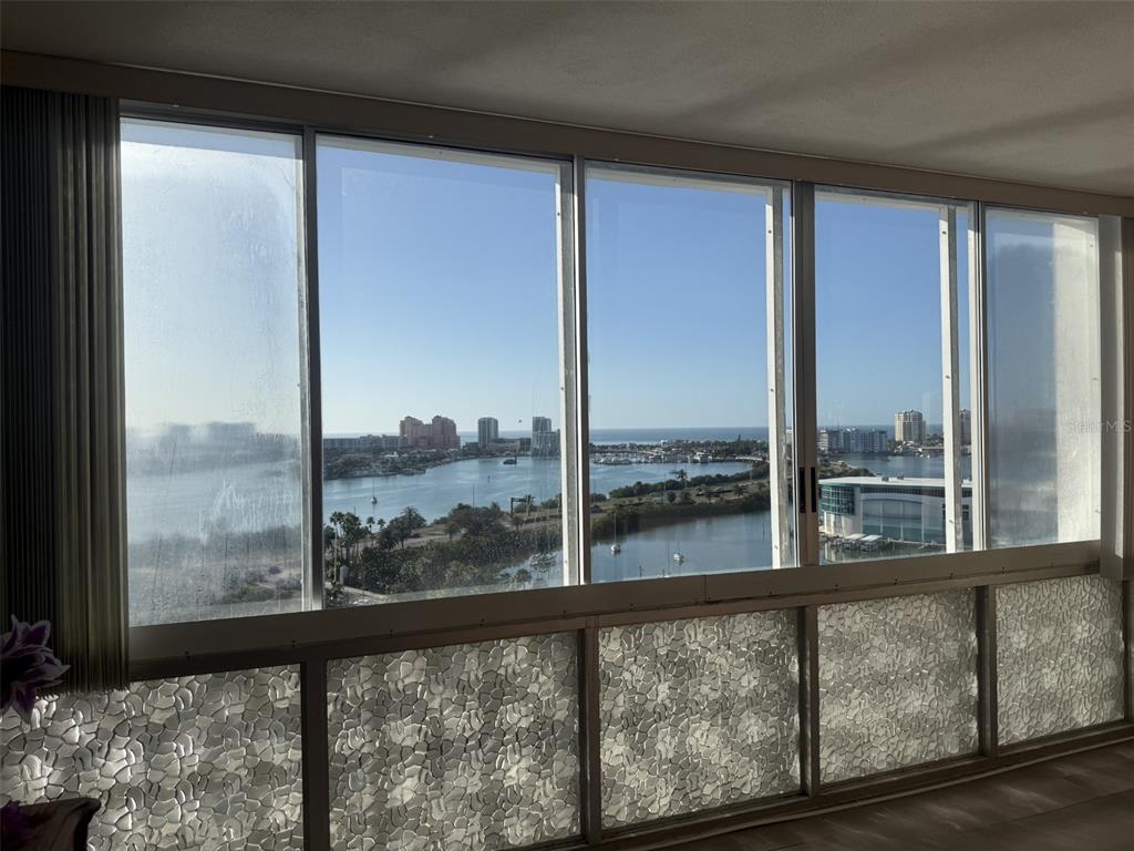 A room with a wall of windows offering a view of a bay and city — 31 ISLAND WAY UNIT 1205, CLEARWATER BEACH, FL