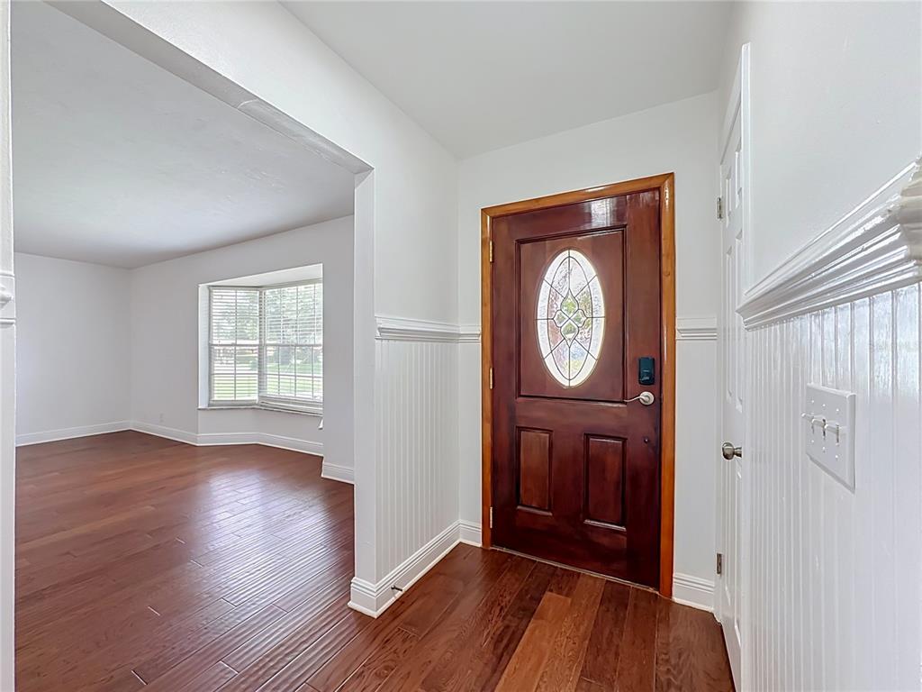 An entryway with wood flooring, white wainscoting, and a wooden front door with a glass insert — 514 W HILDA DRIVE, BRANDON, FL