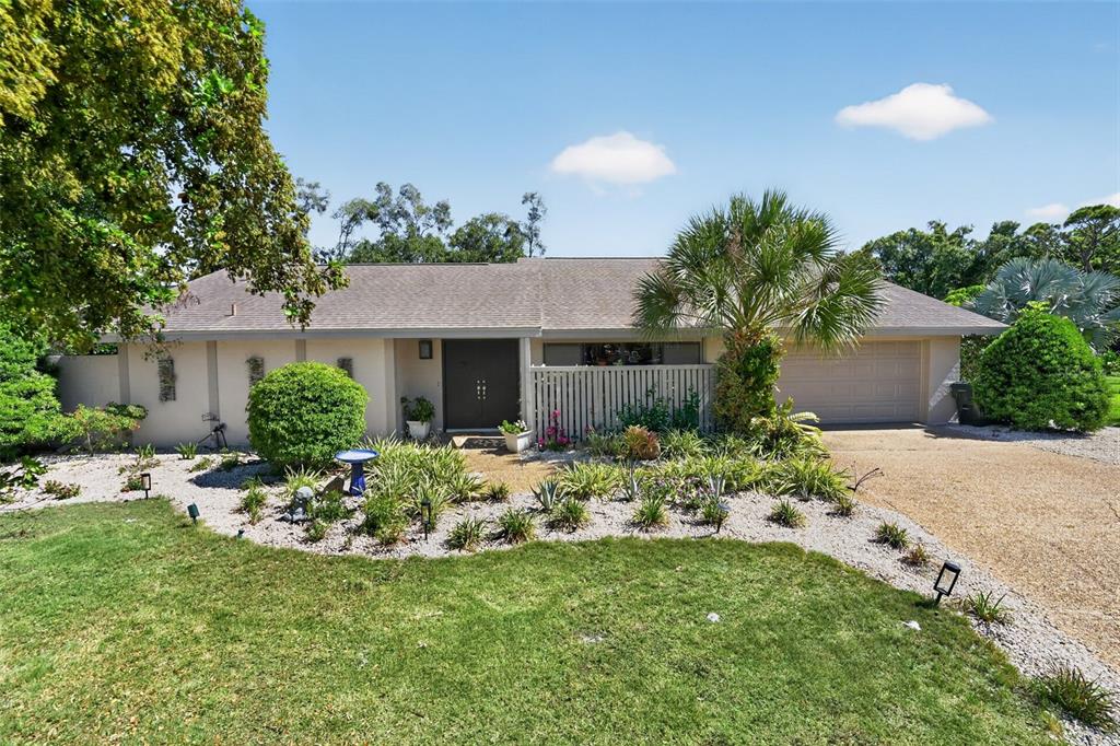 A single-story house with a gravel driveway, a palm tree, and a landscaped front yard — 3935 COUNTRY VIEW LANE, SARASOTA, FL