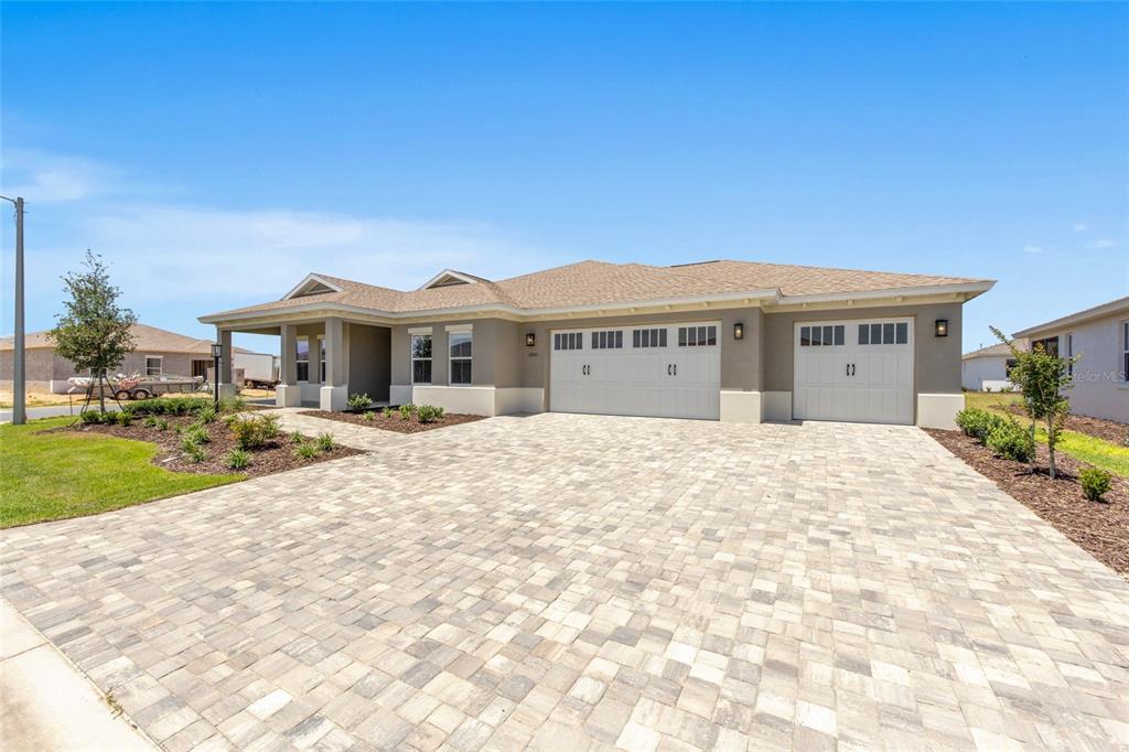 A single-story house with a beige exterior, a three-car garage, and a paved driveway — 10261 SW 82ND PLACE ROAD, OCALA, FL