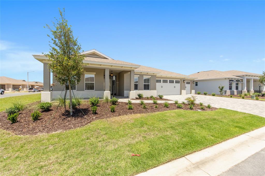 A single-story house with a beige exterior, a paved driveway, and a landscaped front yard — 10261 SW 82ND PLACE ROAD, OCALA, FL
