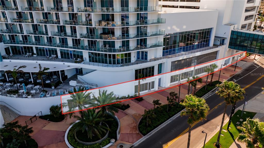 An aerial view shows the exterior ground level of a modern hotel with palm trees — 400 CORONADO DRIVE, CLEARWATER BEACH, FL