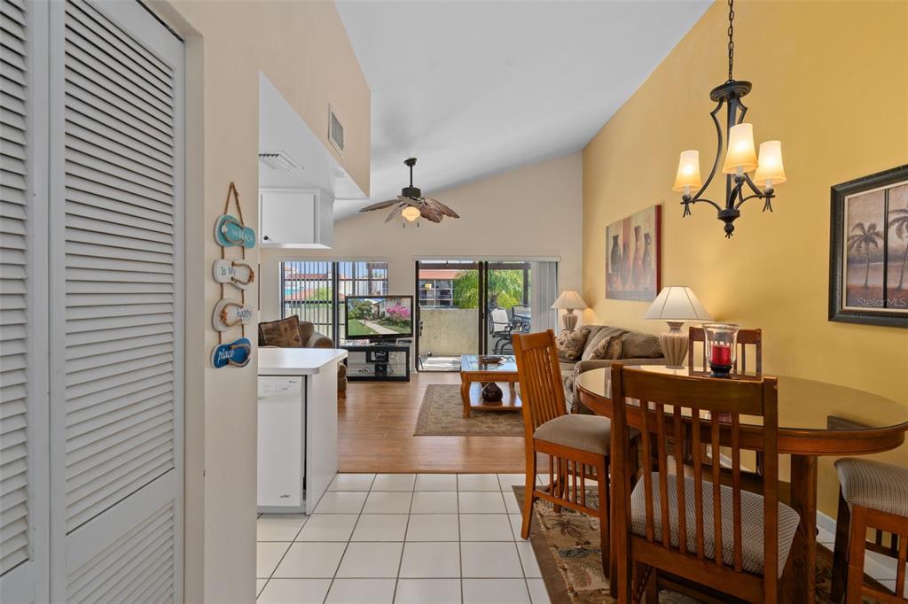 A dining area with a glass table and chandelier opens into a living room — 2571 CYPRUS DRIVE UNIT 1-201, PALM HARBOR, FL