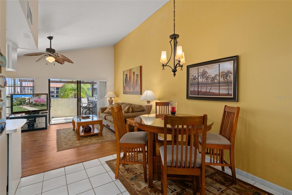 A dining area with a glass table and chairs sits beside a living room with furniture — 2571 CYPRUS DRIVE UNIT 1-201, PALM HARBOR, FL