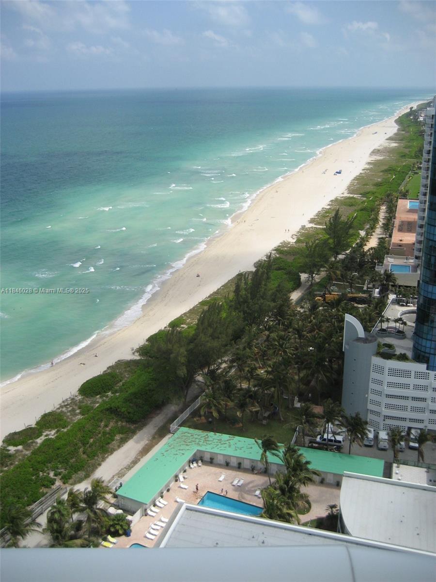 An elevated view of a sandy beach, turquoise ocean, and a nearby swimming pool — 6365 Collins Ave # 3907, Miami Beach FL 33141, MIAMI BEACH, FL