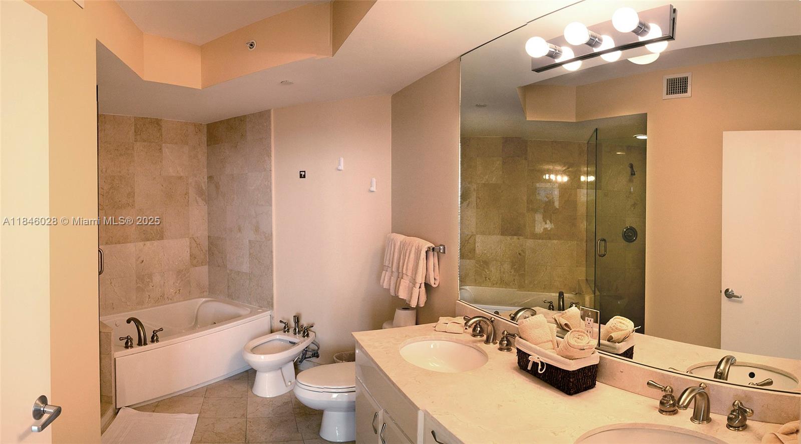 A bathroom features a soaking tub, a toilet, and a vanity with a large mirror — 6365 Collins Ave # 3907, Miami Beach FL 33141, MIAMI BEACH, FL