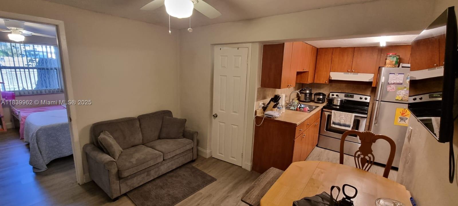 This open-concept living area features a gray sofa, a dining table, and a small kitchen — 7230 NW 3rd St, Miami FL 33126, MIAMI, FL