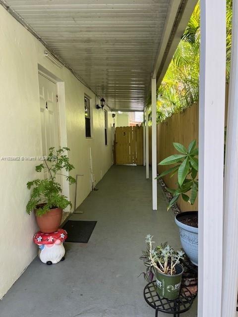 A covered outdoor walkway leads to a doorway with potted plants on a concrete floor — 7230 NW 3rd St, Miami FL 33126, MIAMI, FL