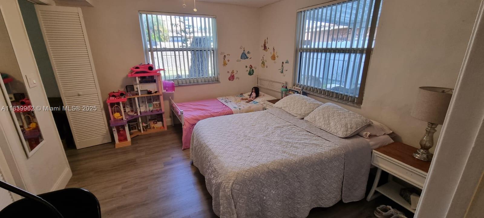 A bedroom features a double bed, a twin bed, a dollhouse, and light-colored wood flooring — 7230 NW 3rd St, Miami FL 33126, MIAMI, FL