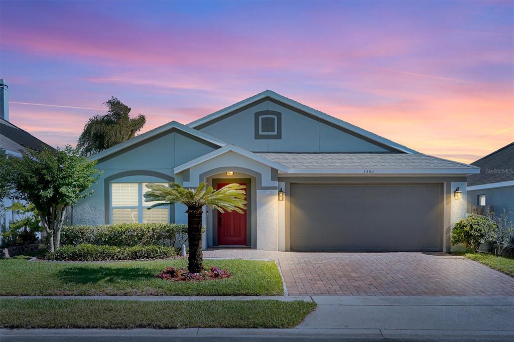 A single-story house with a red front door, a two-car garage, and a palm tree — 1361 HOLLY GLEN RUN, APOPKA, FL