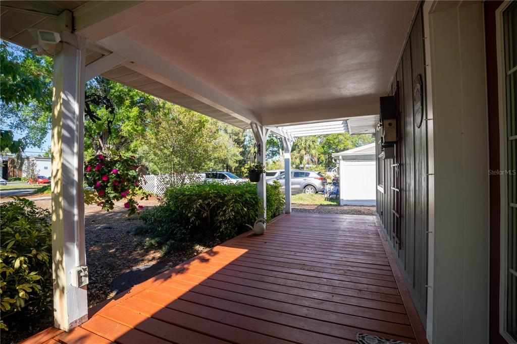 A wooden front porch features a covered roof, a hanging plant, and a white railing — 2567 CENTRAL AVENUE, CLEARWATER, FL