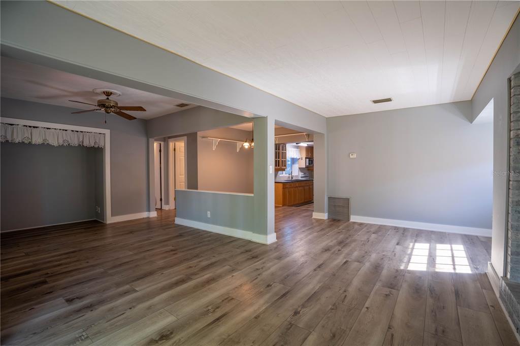 An open-concept living area features gray walls, wood-look flooring, and a view into the kitchen — 2567 CENTRAL AVENUE, CLEARWATER, FL