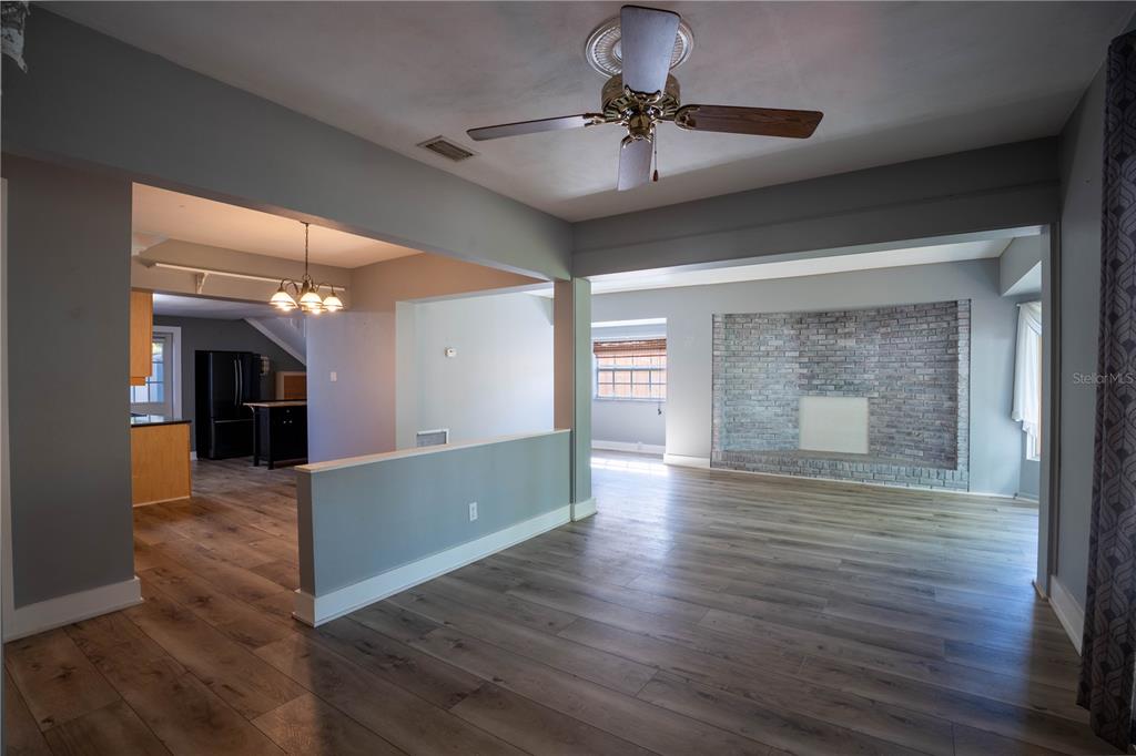 An open-concept living area features wood-look flooring, a gray brick fireplace, and a ceiling fan — 2567 CENTRAL AVENUE, CLEARWATER, FL