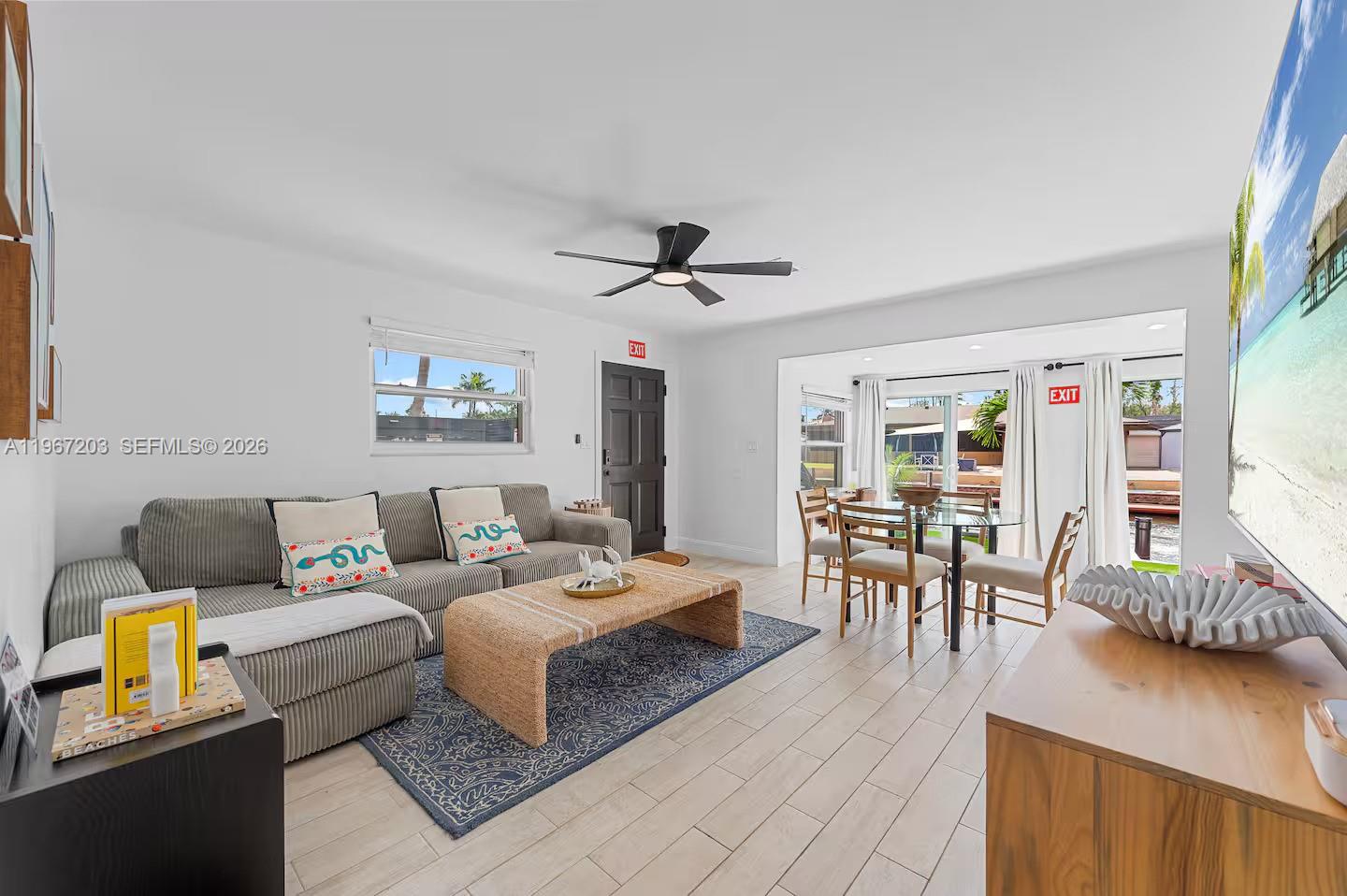 A living room features a gray sofa, a woven coffee table, and a dining area — 1469 NW 10th St, Dania Beach FL 33004, DANIA BEACH, FL
