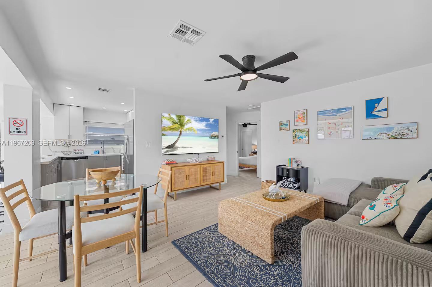 An open-concept living and dining area features a glass table, sofa, and wall-mounted television — 1469 NW 10th St, Dania Beach FL 33004, DANIA BEACH, FL