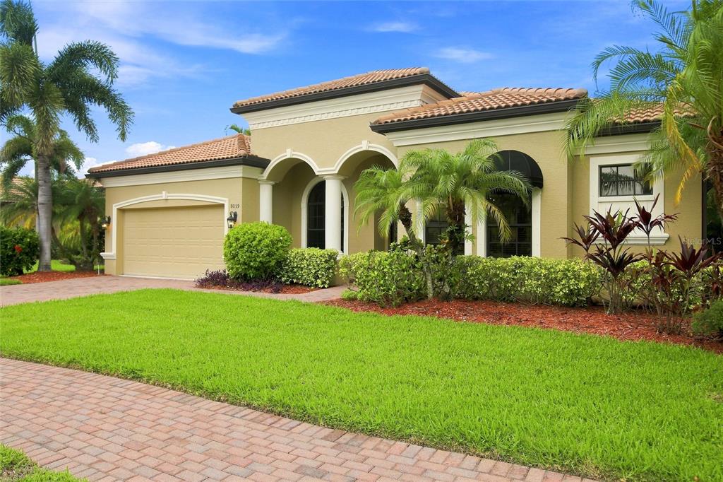 A single-story house with a tan stucco exterior, tile roof, and a paved driveway — 8059 36TH STREET CIRCLE E, SARASOTA, FL