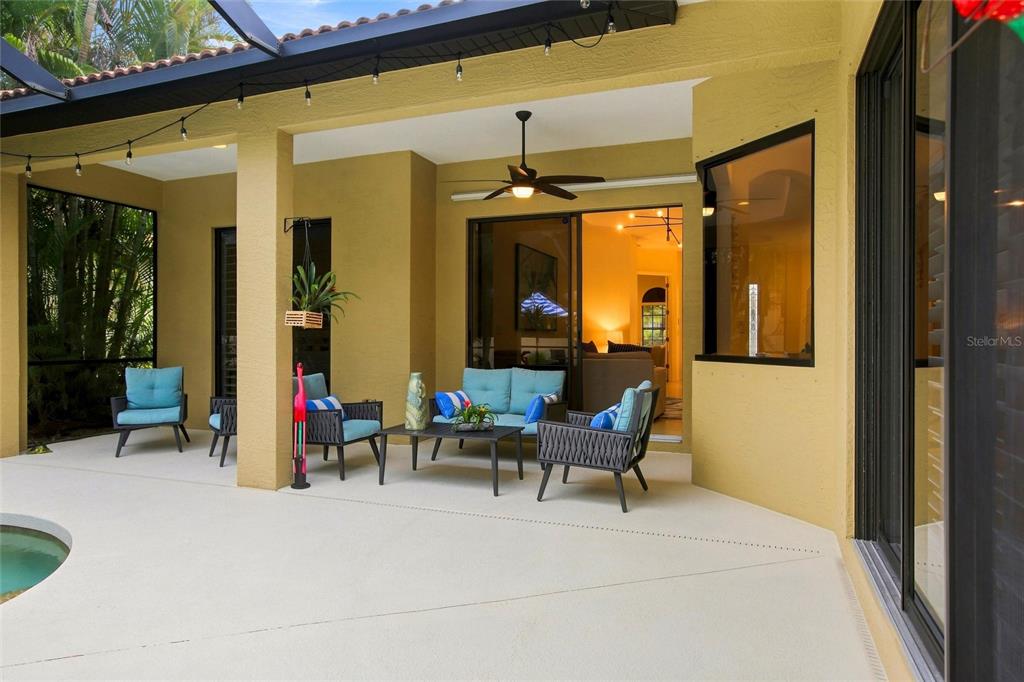 A covered patio features outdoor furniture, a ceiling fan, and a view of a pool — 8059 36TH STREET CIRCLE E, SARASOTA, FL