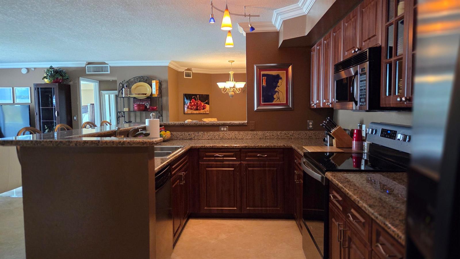A kitchen features dark wood cabinets, granite countertops, and an open view into the dining area — 3606 S Ocean Boulevard # 303, Highland Beach FL 33487, HIGHLAND BEACH, FL