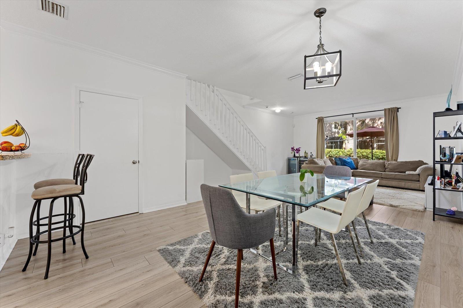 An open-concept dining and living area features light wood flooring, a glass table, and stairs — 2264 Salerno Circle, Weston FL 33327, WESTON, FL