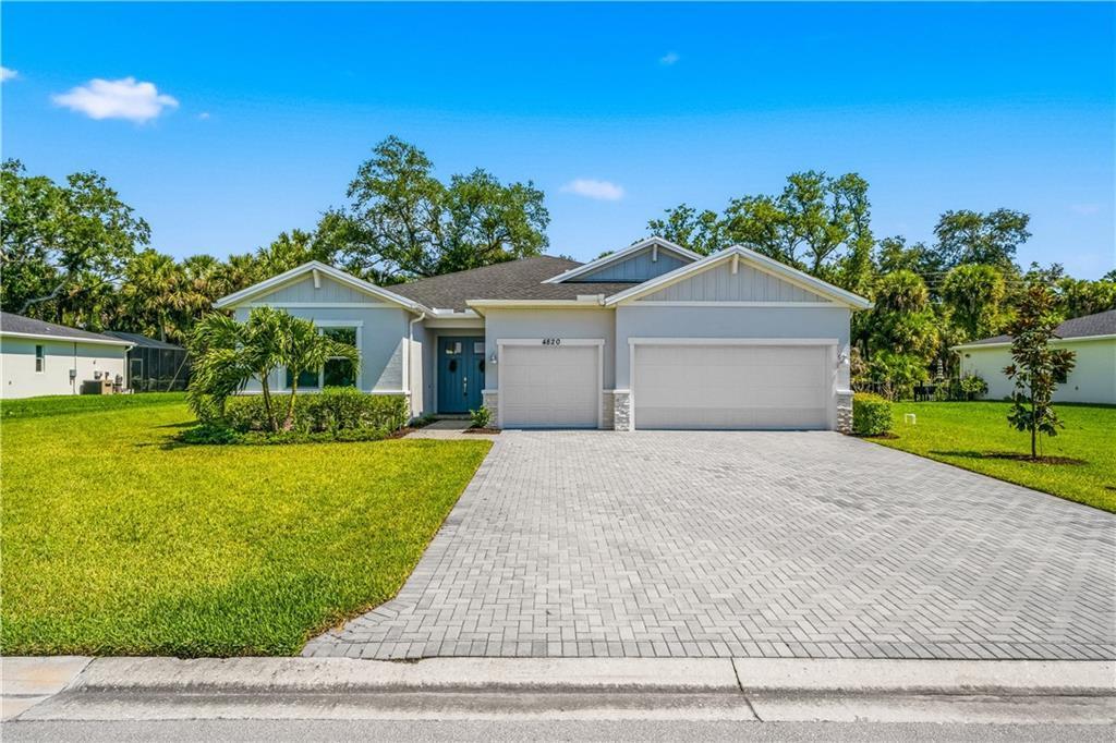 A single-story house with a paved driveway, two garage doors, and a blue front door — VERO BEACH, FL