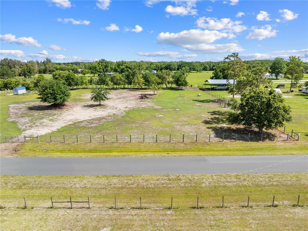 An aerial view shows a fenced, grassy lot with scattered trees and a small shed — HUNTING LODGE DRIVE, ST CLOUD, FL