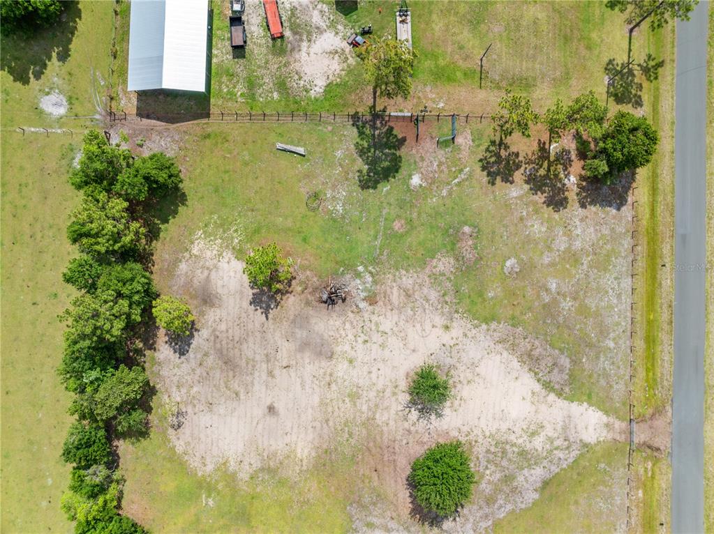 An aerial view shows a grassy, partially cleared lot with scattered trees and a metal building — HUNTING LODGE DRIVE, ST CLOUD, FL