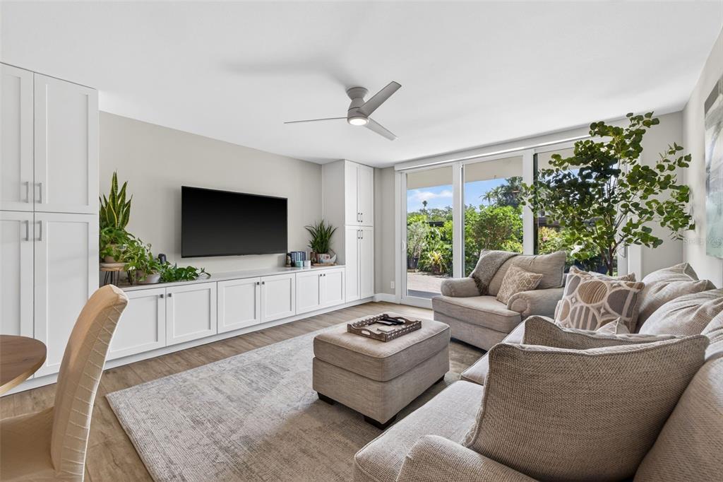 A living room features white built-in cabinetry, a television, a sofa, and a sliding glass door — 100 OAKMONT LANE UNIT 107 & 108, BELLEAIR, FL