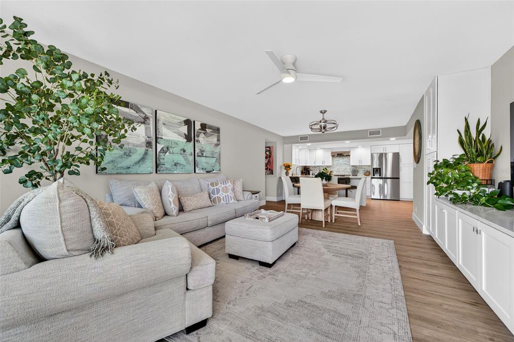 A living room with light gray furniture, a large area rug, and an open kitchen — 100 OAKMONT LANE UNIT 107 & 108, BELLEAIR, FL