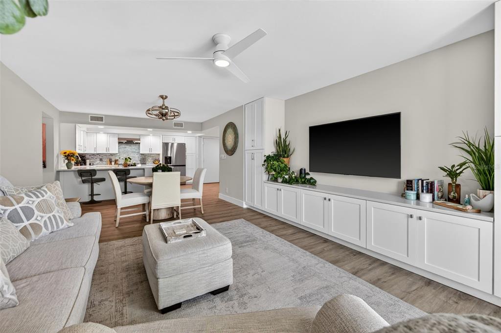 A living room features a white media console, a grey sectional, and an open kitchen — 100 OAKMONT LANE UNIT 107 & 108, BELLEAIR, FL