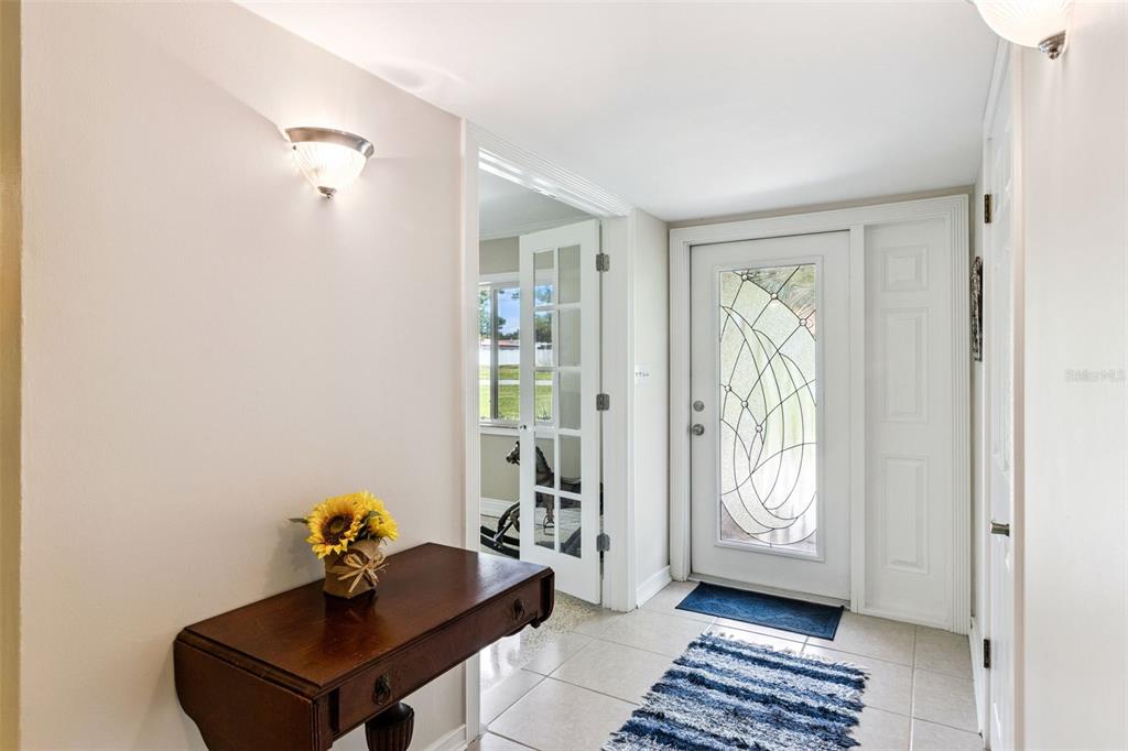 An entryway features a wooden console table, a decorative front door, and a tiled floor — 101 RONELE DRIVE, BRANDON, FL