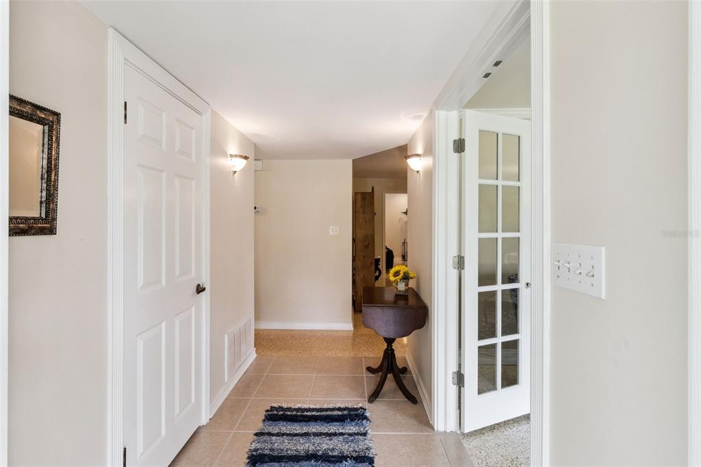 A hallway with tiled floors, a small wooden table, and a white French door — 101 RONELE DRIVE, BRANDON, FL