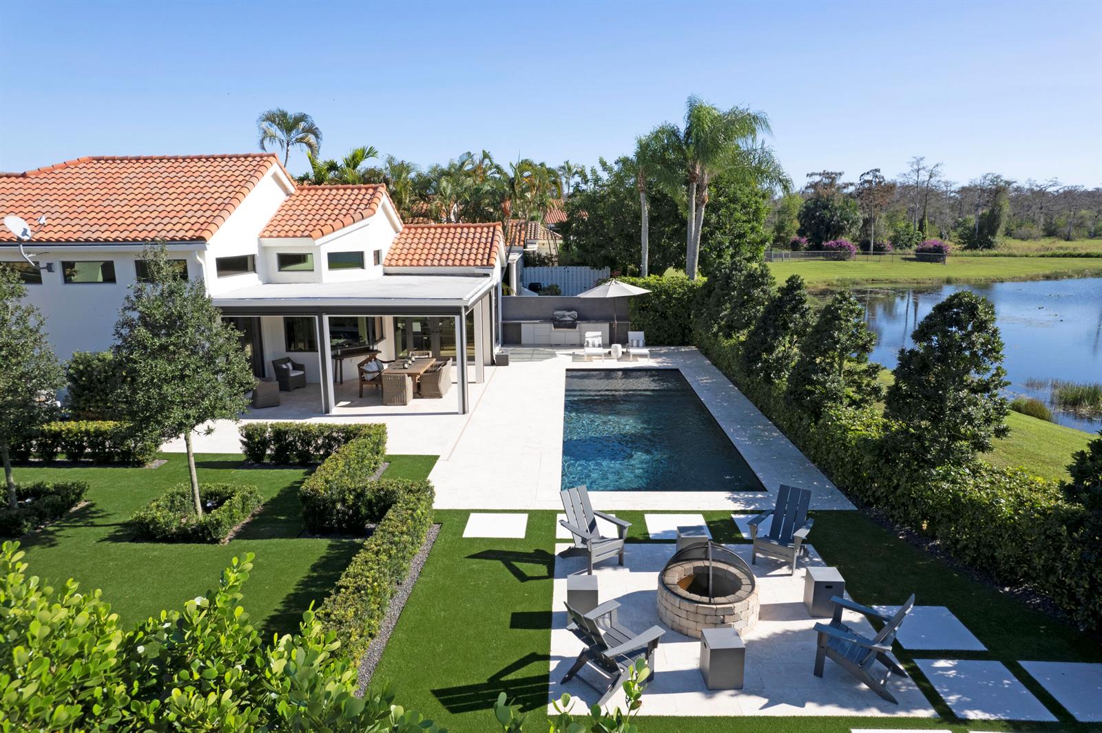 An aerial view of a backyard featuring a pool, fire pit, patio, and lake view — 12570 Mallet Circle, Wellington FL 33414, WELLINGTON, FL