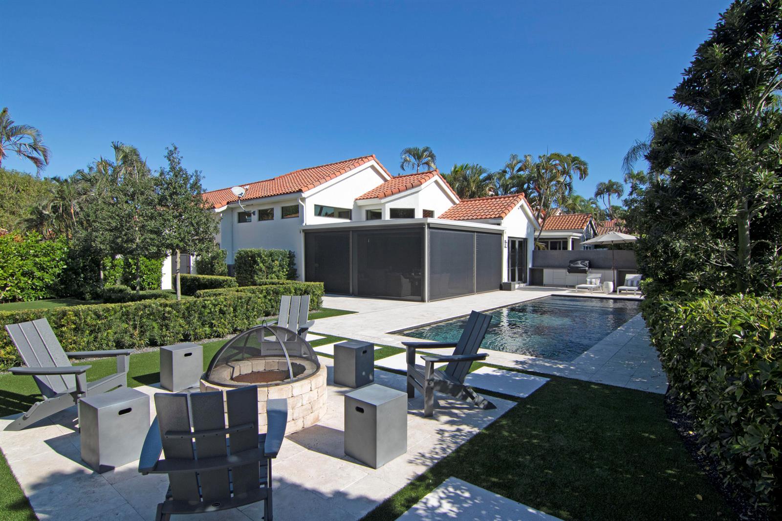 A backyard features a swimming pool, a fire pit with Adirondack chairs, and a patio — 12570 Mallet Circle, Wellington FL 33414, WELLINGTON, FL