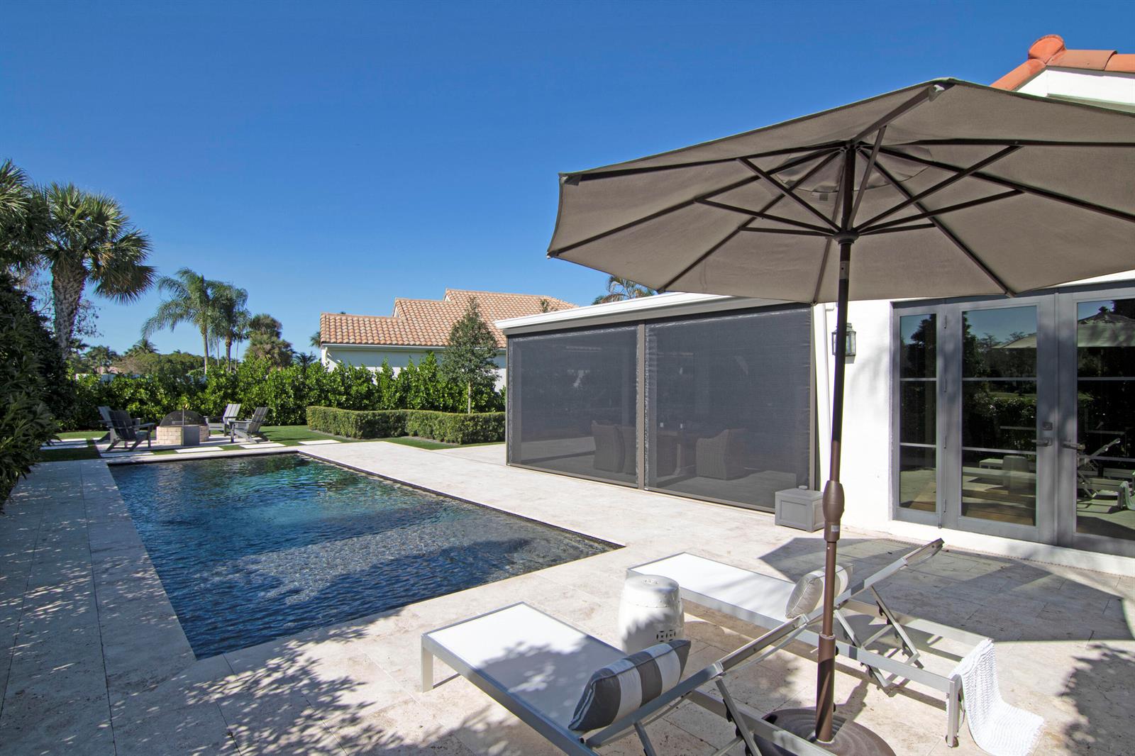 A backyard patio features a swimming pool, lounge chairs, a patio umbrella, and a screened enclosure — 12570 Mallet Circle, Wellington FL 33414, WELLINGTON, FL