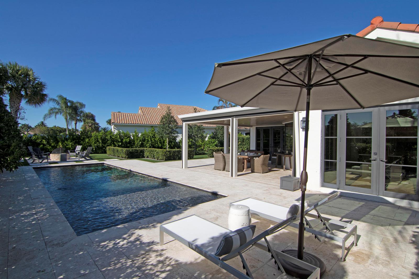 A backyard patio features a swimming pool, lounge chairs with an umbrella, and a covered dining area — 12570 Mallet Circle, Wellington FL 33414, WELLINGTON, FL